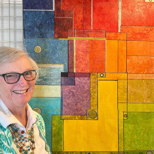 An artist woman pausing with her painting with geometric shapes in rainbow colors