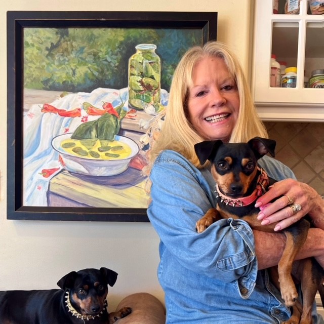 woman posing before her painting with her 2 dogs