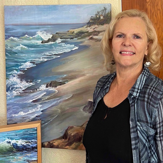 woman posing before her painting of beach